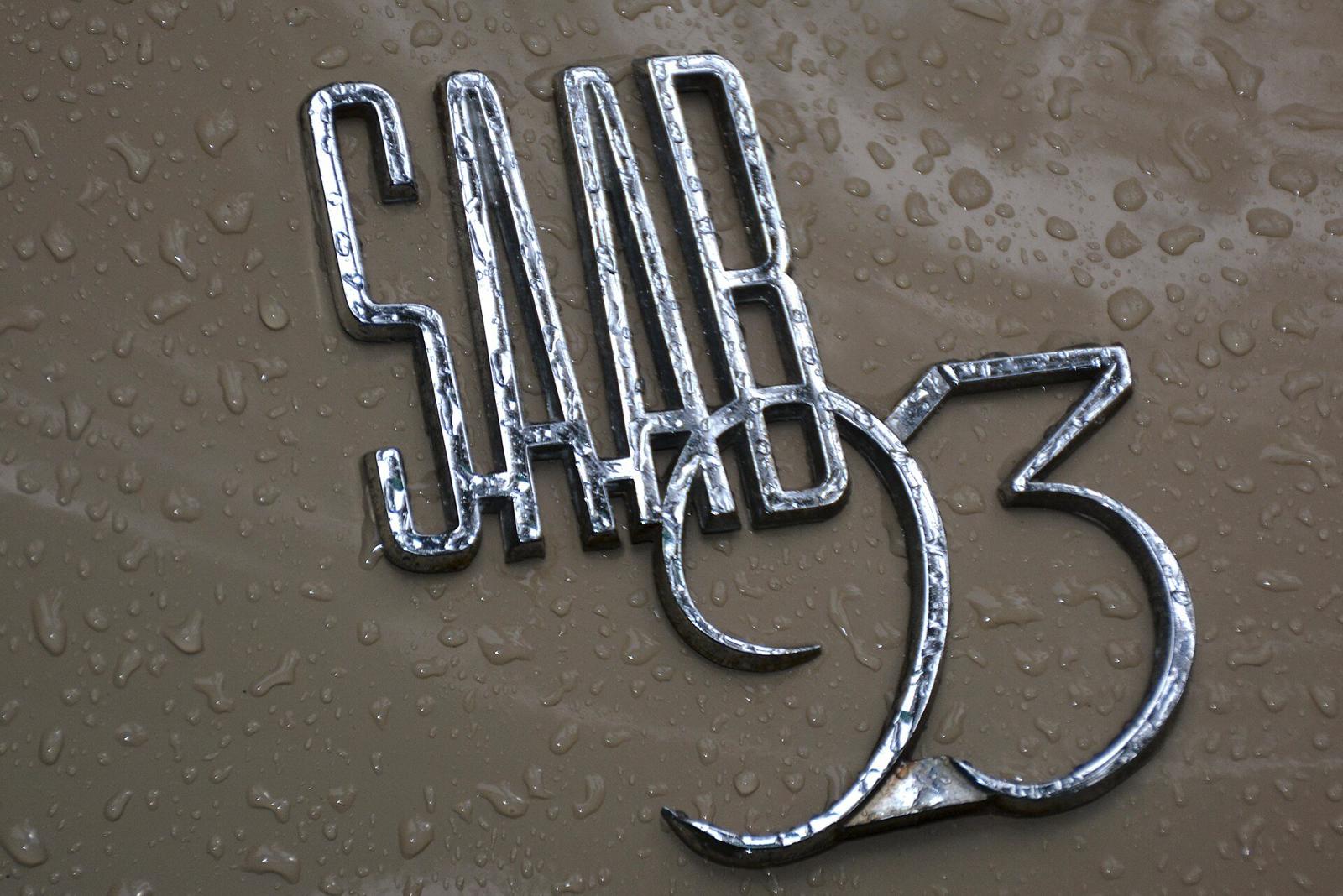 Forkrommet Saab 93-skriftmerke på grå lakk med regndråper