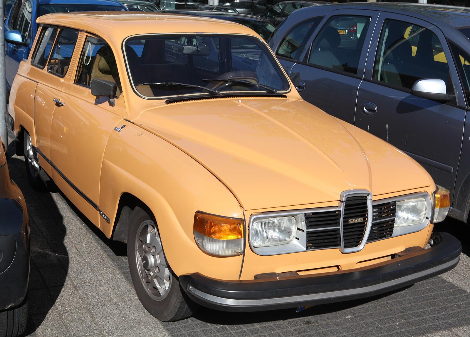 Oransje Saab 95 GL V4 fra 1978 med svart plastgrill, på en parkeringsplass