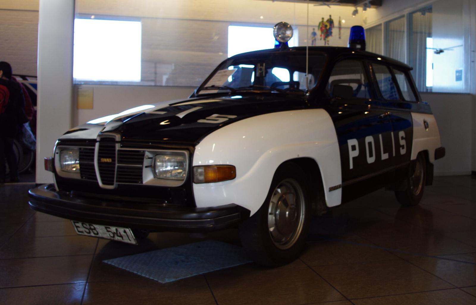 Svart og hvit Saab 95 V4 merket POLIS, utstilt innendørs