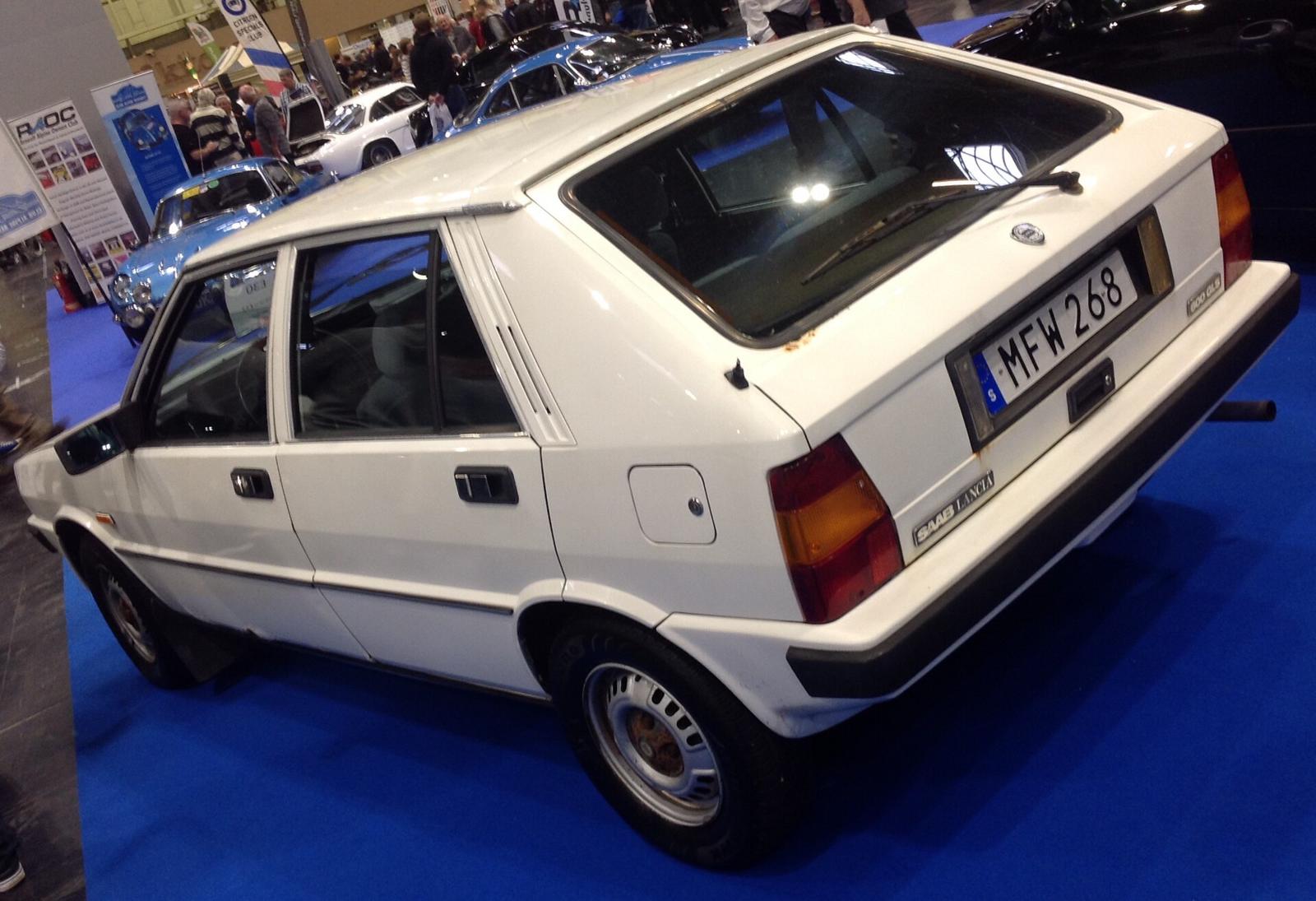 Hvit Saab-Lancia 600 GLS sett skrått bakfra på en utstilling med blått gulvteppe