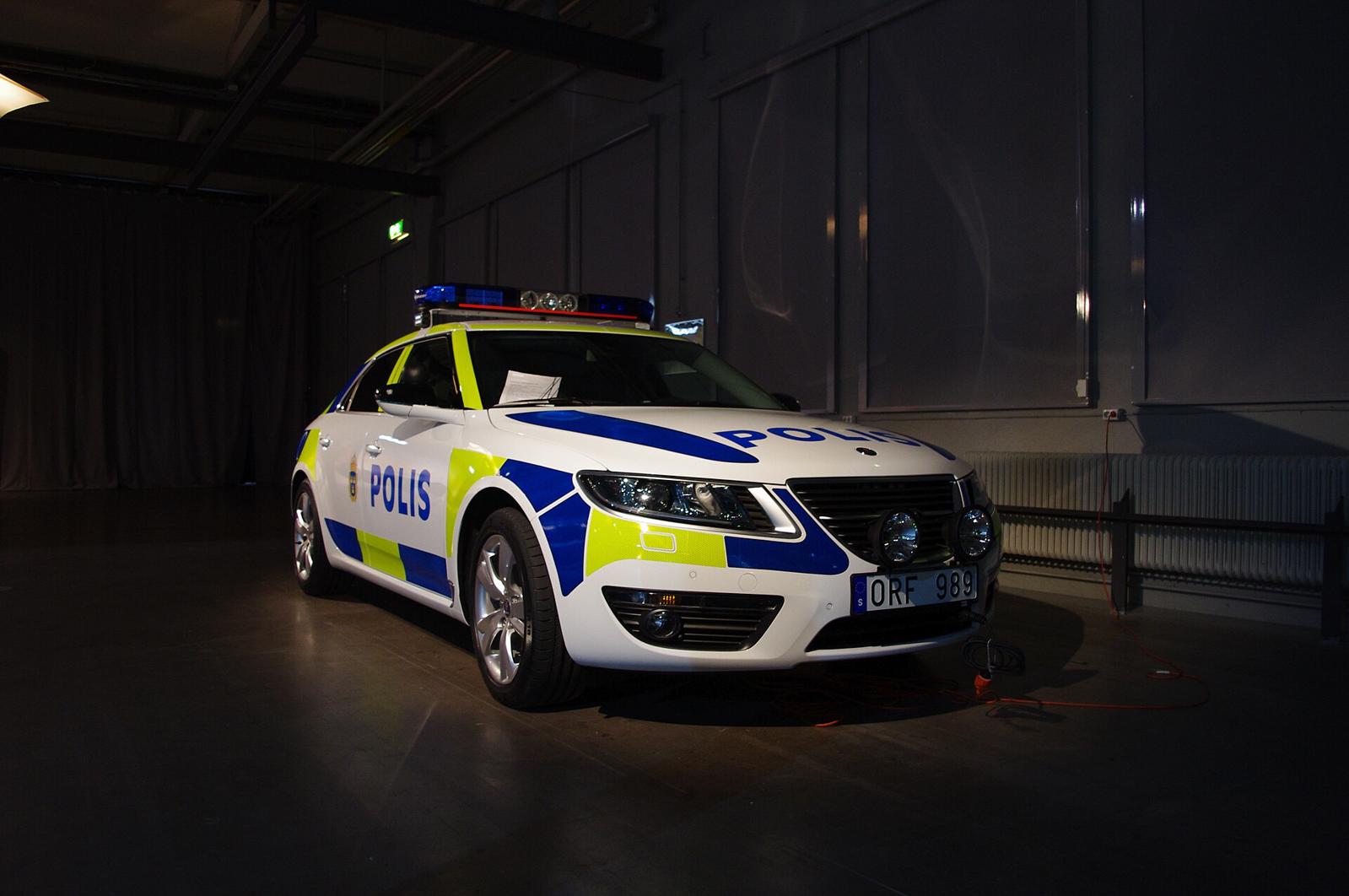 Saab 9-5 i gul og blå svensk politidekor med blålys på taket, innendørs