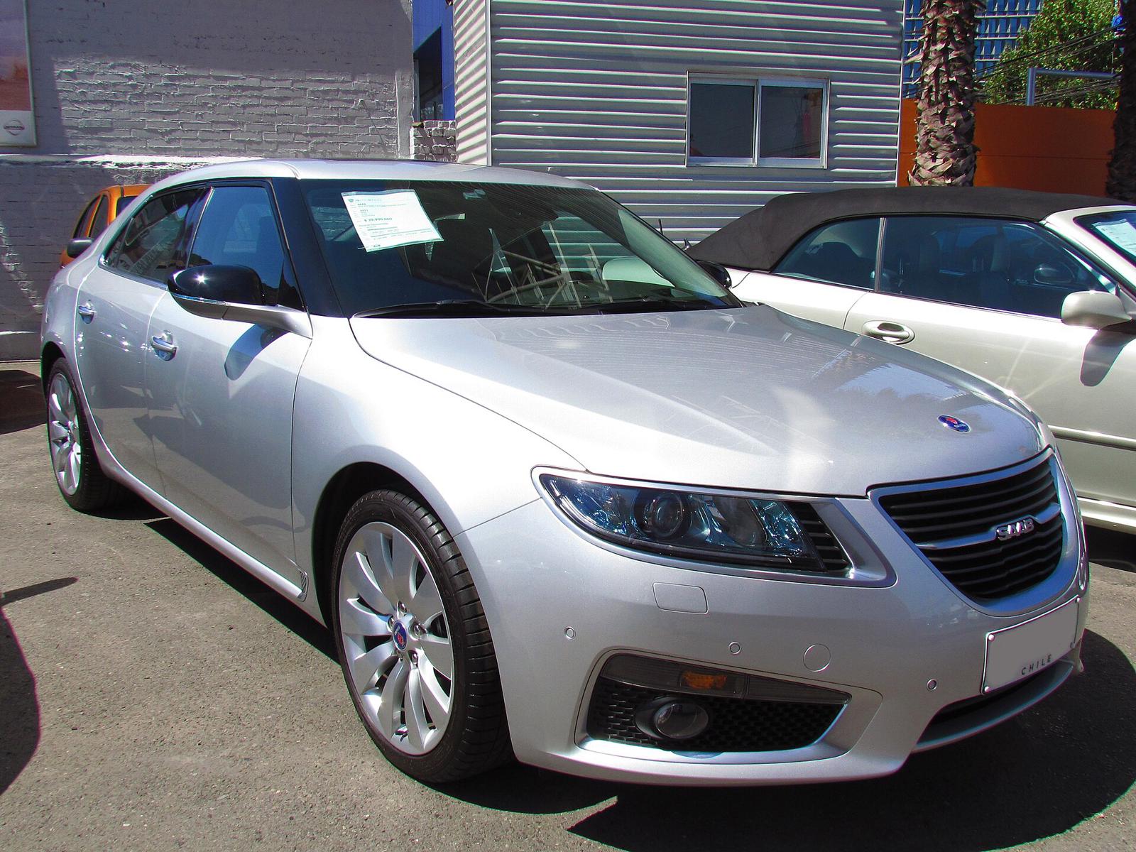 Sølvfarget Saab 9-5 Aero sett skrått forfra, parkert foran en kabriolet