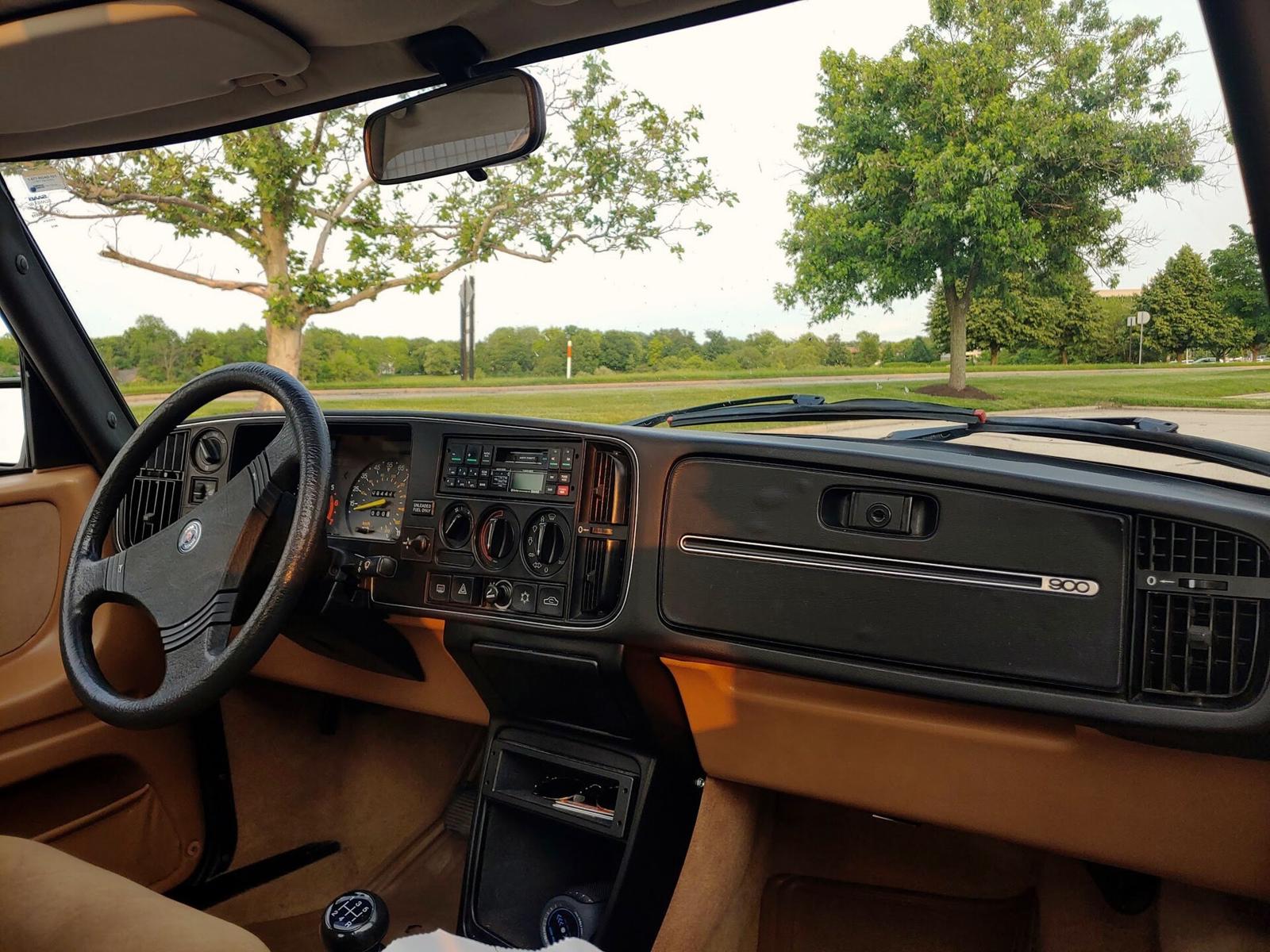Førerplassen i en Saab 900 med svart, buet dashbord og lyst brunt interiør