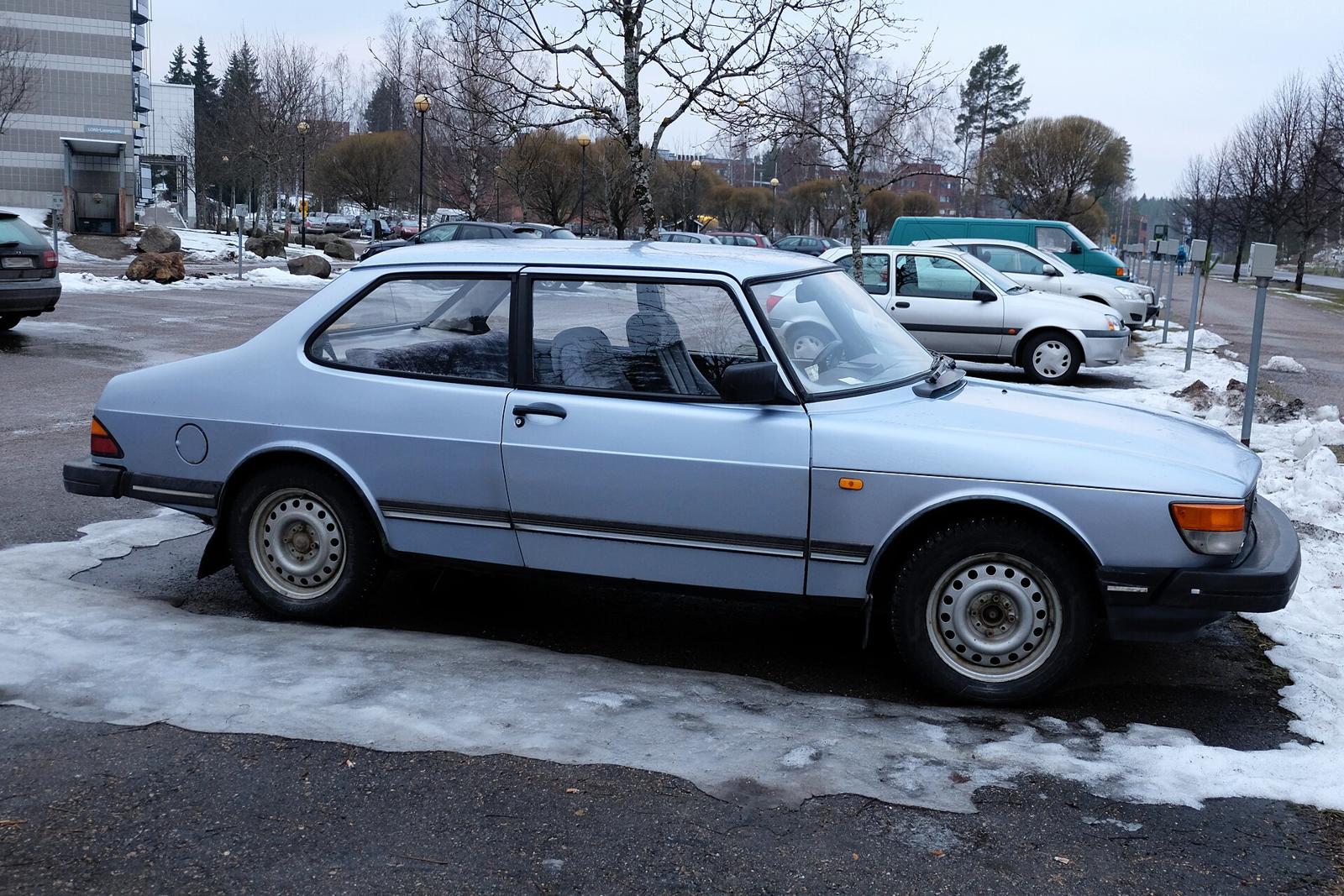 Lyseblå Saab 90 sett fra siden på en parkeringsplass med snø