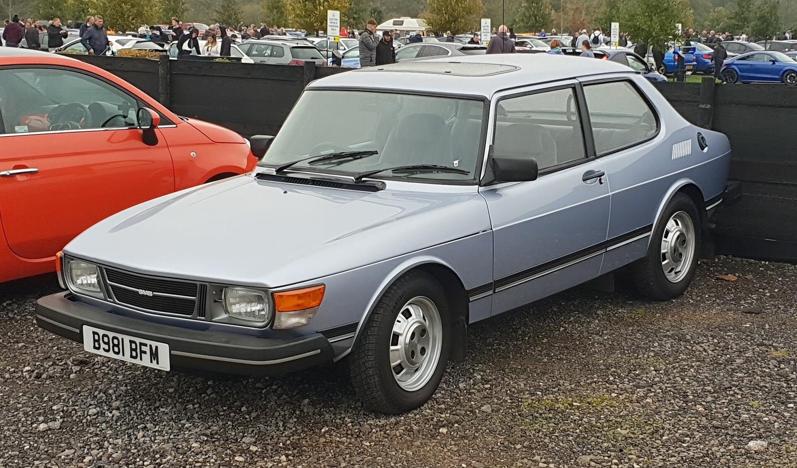 Lyseblå Saab 90 med britiske skilter og soltak, parkert på grus