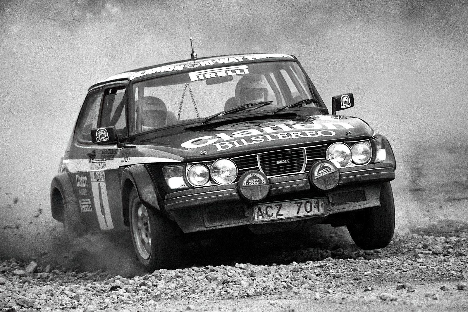 Svart-hvitt bilde av en Saab 99 Turbo rallybil med ekstralys på grusvei