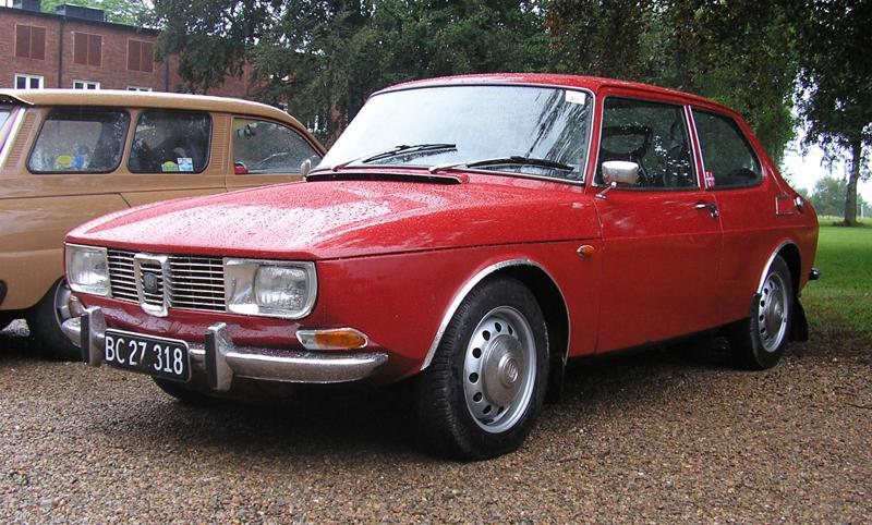 Rød todørs Saab 99 fra 1969 parkert på grus
