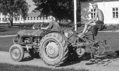 Sørum prestegård i 1960-åra. Hanne og Trond Løfsgaard på vei med traktor og radrenser. Sørum skole i bakgrunnen. 